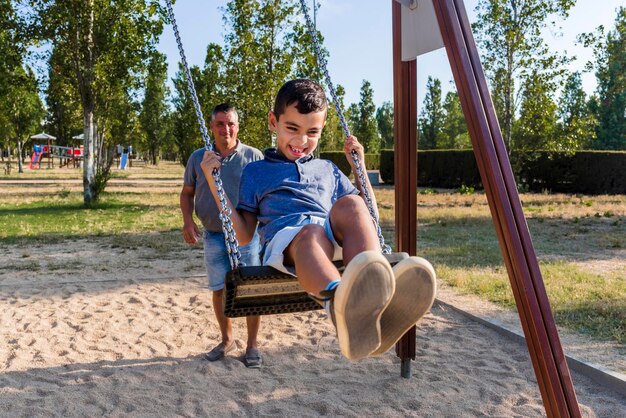 Padre e hijo divirtiéndose jugando con el columpio en un parque