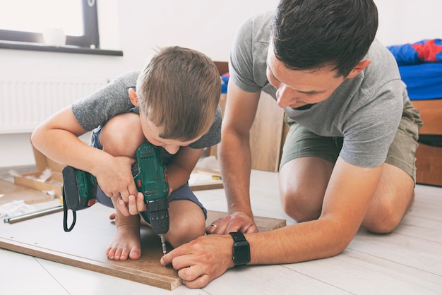 Padre e hijo ensamblando el escritorio y el padre le enseña a su hijo a usar herramientas