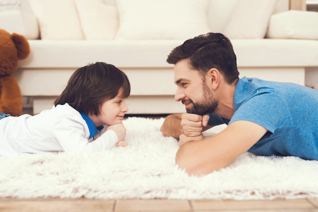 Padre e hijo está acostado en la alfombra en casa.