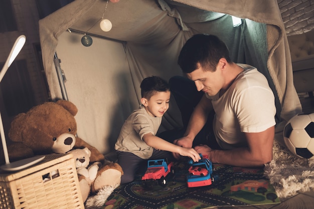 Padre e hijo están jugando con los coches por la noche.