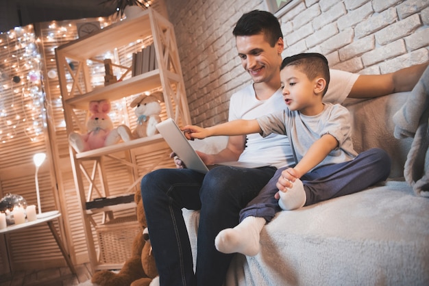 Padre e hijo están viendo la película en la computadora portátil.