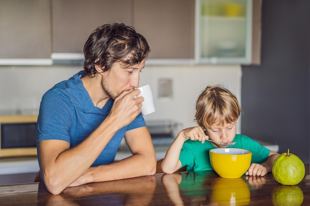 Padre e hijo hablan y sonríen mientras desayunan en la cocina