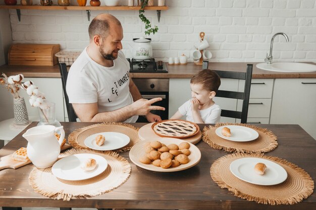 Foto padre e hijo hablando y sonriendo mientras desayunan en la cocina en la mesa