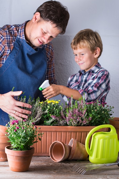 Padre e hijo haciendo huerto urbano en casa. Actividad que estimula la salud mental y cerebral. Plantar y cultivar flores de otoño, pasatiempo y ocio ecológicos, concepto de tiempo en familia.