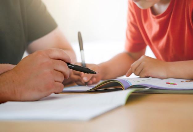 Padre e hijo haciendo la tarea juntos, un maestro enseñando a un niño pequeño a escribir.