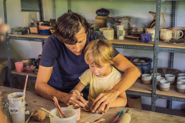 Padre e hijo haciendo vasija de cerámica en taller de cerámica