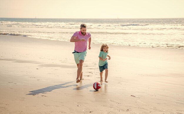 Padre e hijo juegan fútbol o fútbol en la playa papá con niño en verano