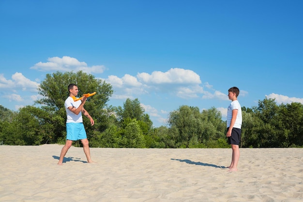 Padre e hijo juegan juegos de verano de vacaciones en la playa Deportes recreativos de estilo de vida