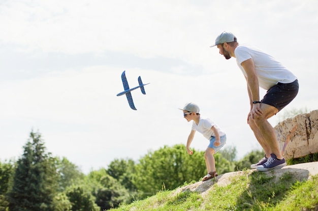 Padre e hijo juegan en el parque con un avión de juguete