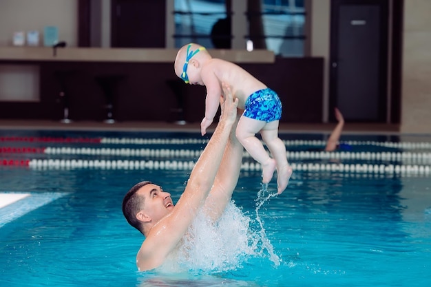 Padre e hijo juegan en la piscina. el padre arroja al hijo.