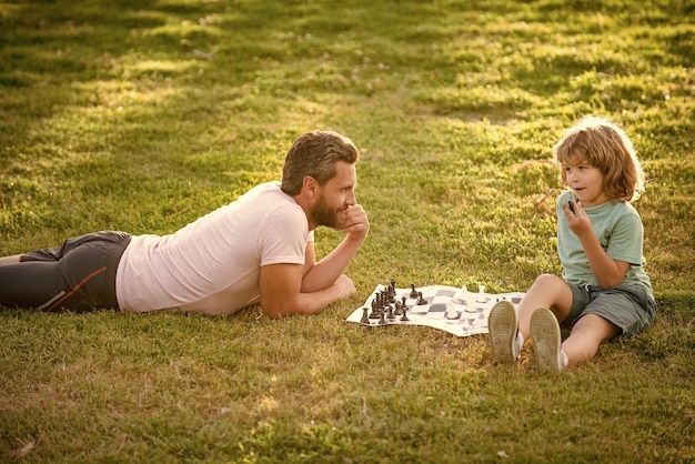 Padre e hijo jugando al ajedrez en el césped en el parque día del padre feliz familia paternidad e infancia