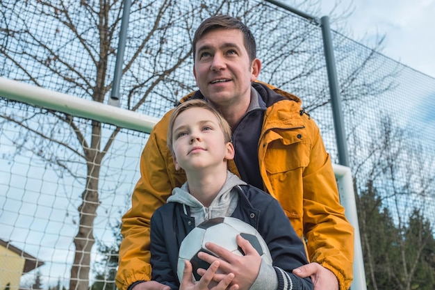 Foto padre e hijo jugando al fútbol en el patio de recreo padre enseña a su hijo a jugar en el campo de fútbol actividad