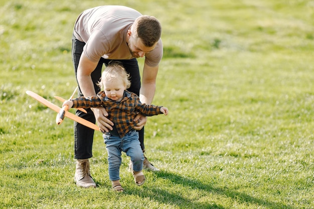 Padre e hijo jugando con un avión de juguete y divirtiéndose en el parque de verano al aire libre Niño rizado niño vistiendo jeans y camisa a cuadros