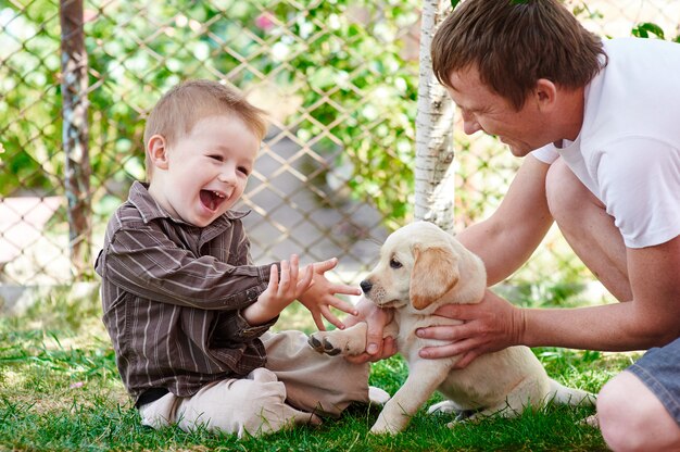 Padre e hijo jugando con un cachorro labrador en el jardín