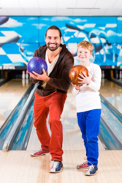 Padre e hijo jugando en el centro de bolos