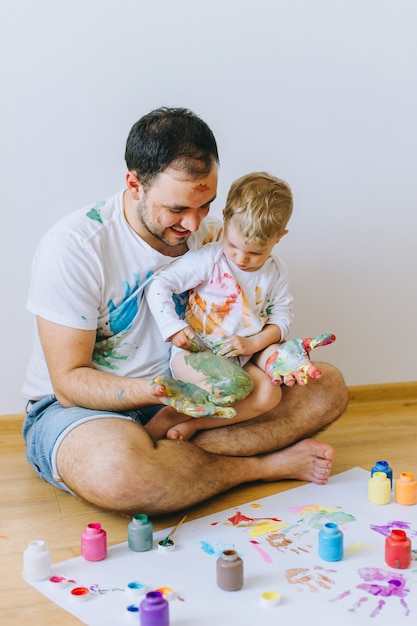 Padre e hijo jugando con colores de pintura