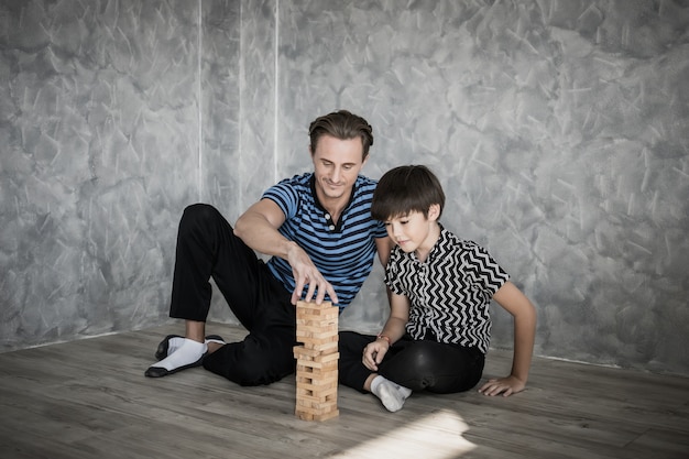 Padre e hijo jugando a Jenga en casa. Concepto de familia feliz.