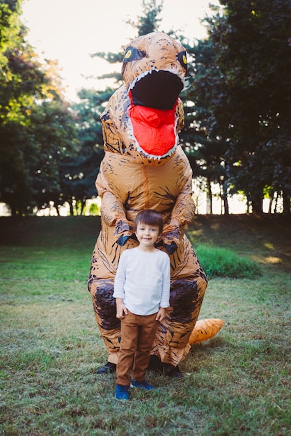 Padre e hijo jugando en el parque, con un disfraz de dinosaurio, divirtiéndose con la familia al aire libre