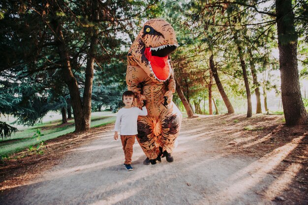 Padre e hijo jugando en el parque, con un disfraz de dinosaurio, divirtiéndose con la familia al aire libre