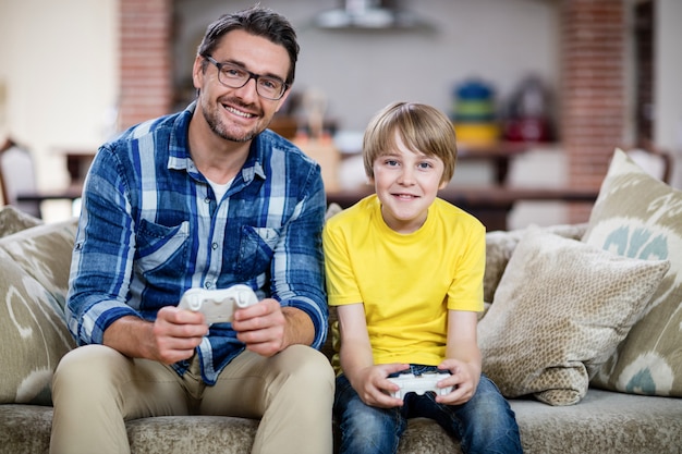 Padre e hijo jugando videojuegos en el sofá