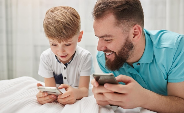 Foto padre e hijo jugando videojuegos en teléfonos inteligentes