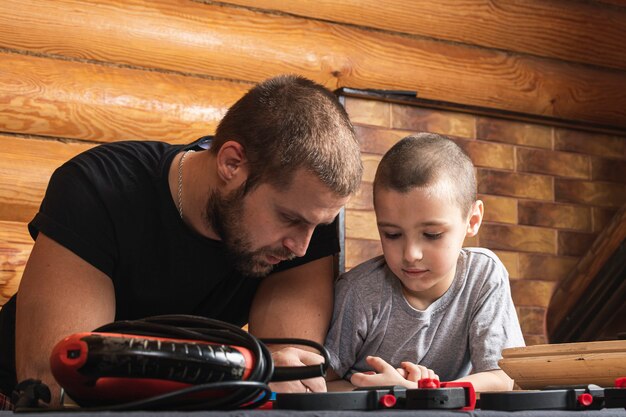 Foto padre e hijo juntos hacen una pajarera de madera en el taller.