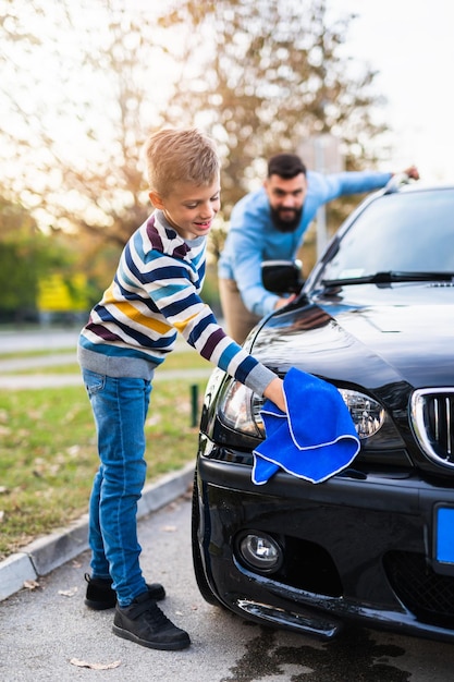 Padre e hijo lavando su coche juntos.