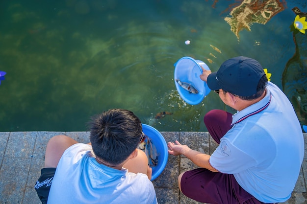 Padre e hijo liberan peces KOI cerca de un lago La pesca de captura y liberación mejora las poblaciones de peces nativos al permitir que más peces permanezcan y se reproduzcan en el ecosistema