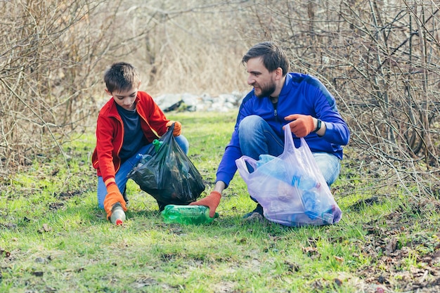 Padre e hijo limpian el parque de basura voluntarios limpian el bosque de botellas de plástico y pasan tiempo juntos