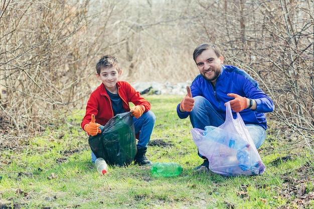 Padre e hijo limpian el parque de basura voluntarios limpian el bosque de botellas de plástico y pasan tiempo juntos