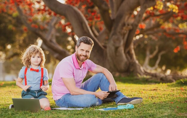 Padre e hijo en línea de negocios de hombre de familia trabajando en el control remoto de la computadora portátil en el parque