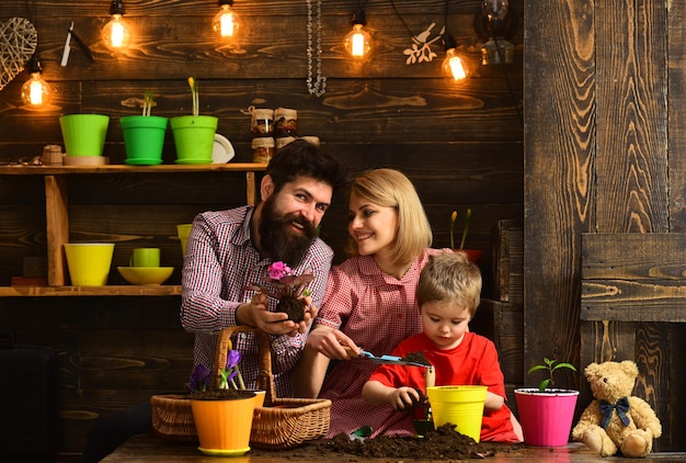 Padre e hijo con madre Cuidado de las flores riego Fertilizantes del suelo mujer hombre y niño pequeño amor naturaleza jardineros felices con flores de primavera Día de la familia Invernadero Solo sonríe