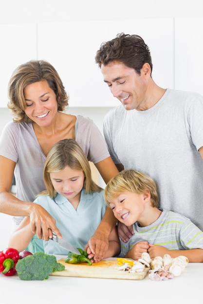 Padre e hijo mirando madre e hija rebanar verduras en la cocina