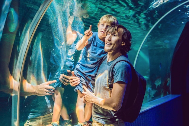 Padre e hijo mirando peces en un acuario de túnel