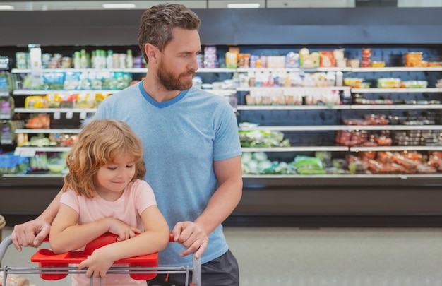 Padre e hijo mirando el producto en la tienda de comestibles. Papá con niño en el supermercado comprando comida.