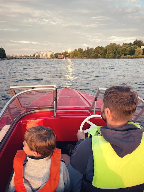 Padre e hijo montando en bote a motor usando chalecos de seguridad dando un paseo en el río Neva San Petersburgo