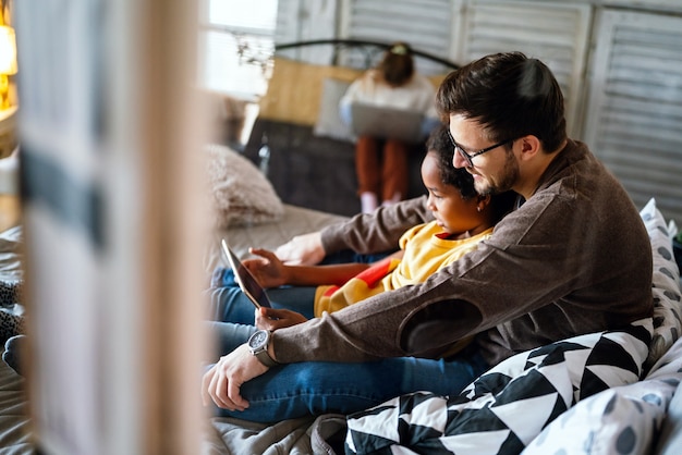 Padre e hijo multiétnicos con tableta electrónica en casa. Tecnología, educación, concepto de personas