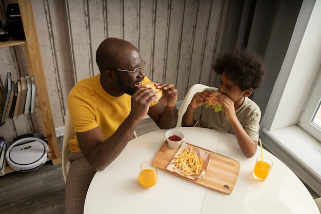 Padre e hijo con papas fritas y hamburguesas juntos