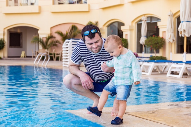 Padre e hijo pequeño pasan tiempo cerca de la piscina en un hotel de lujo en Egipto Hora de la tarde en el resort de verano