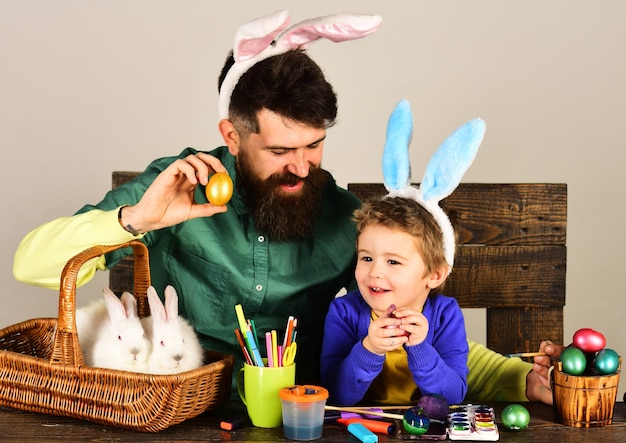 Padre e hijo pintando huevos de Pascua. Familia de Pascua con canasta con huevos pintados.