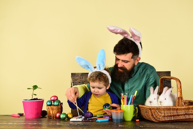 Padre e hijo pintando huevos de Pascua.