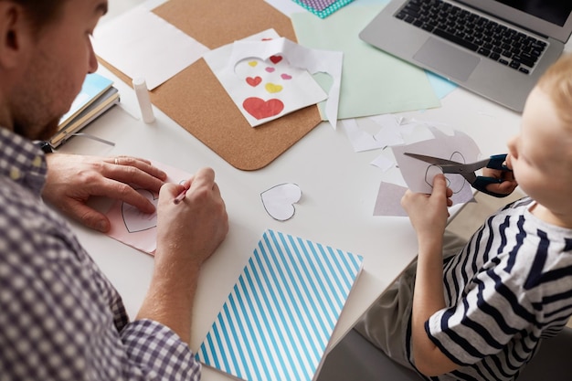 Padre e hijo preparando tarjetas de San Valentín para la madre