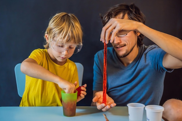 Padre e hijo realizan experimentos químicos en casa. La familia de baba casera juega con una baba.