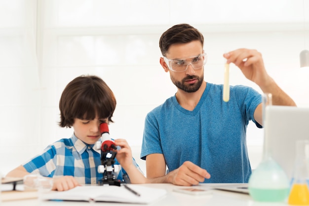 Padre e hijo realizan experimentos químicos en casa.