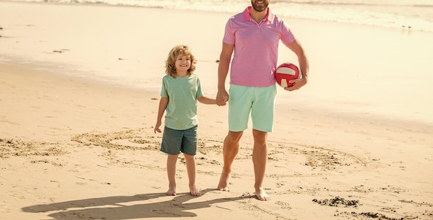 Padre e hijo recortados caminan con pelota en la playa papá con niño en el día de verano