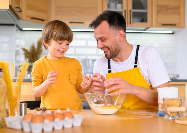 Padre e hijo rompiendo huevos para cocinar