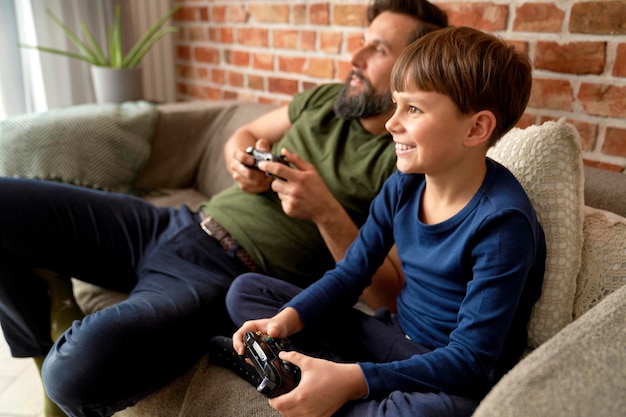 Padre e hijo sentados en casa jugando videojuegos.