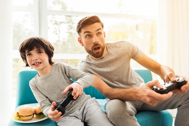 Padre e hijo sentados y jugando en la consola.