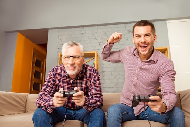 Foto padre e hijo sentados en el sofá y jugando videojuegos