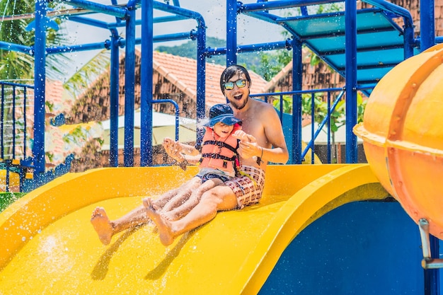 Foto padre e hijo en un tobogán de agua en el parque acuático.